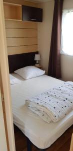 una camera da letto con un letto con lenzuola bianche e una finestra di Camping Siblu les Charmettes la Palmyre a Les Mathes