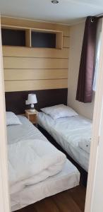 two beds in a room with a lamp on a table at Camping Siblu les Charmettes la Palmyre in Les Mathes