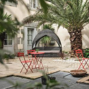un patio con sedie rosse e un tavolo in un cortile di Hotel Le Petit Perier a Laval