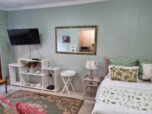 een woonkamer met een bed en een spiegel bij Victorian Villa Westdene Benoni in Benoni