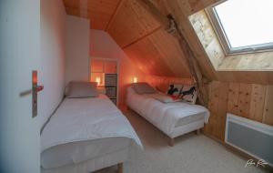 a attic bedroom with two beds and a window at Gîte La Pironnière - Piscine, Nature, au bord de la Rivière in Montreuil-sur-Maine