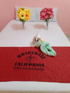 a bed with a red blanket and flowers on it at Hospedaje California Inn in Iquitos