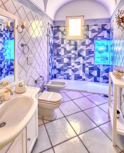 baño azul y blanco con aseo y lavamanos en Le Botteghe 59 Capri en Capri