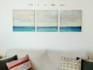 cuatro pinturas del océano en una pared sobre un sofá en Casa Ledù - Sunny Holiday in Fuerteventura, en Corralejo