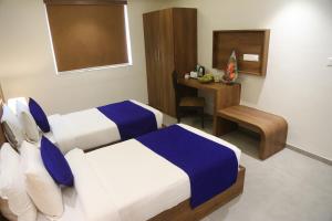 una camera d'albergo con 2 letti e una scrivania di Hotel Nova Pride a Rajkot