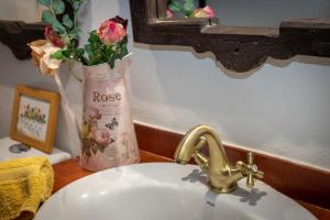 un lavandino in bagno con un vaso di fiori accanto ad esso di Moinho Monte Adão a Vila Franca do Rosário