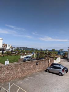 zwei Autos auf einem Parkplatz neben einer Ziegelwand geparkt in der Unterkunft New Esplanade Court Beachfront One bedroom Apartment with Free parking and Seasonal Swimming pool in Paignton