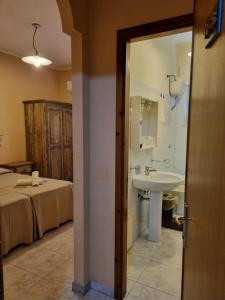 ein Bad mit einem Bett und einem Waschbecken in einem Zimmer in der Unterkunft Hotel Plammas in Santa Maria Navarrese