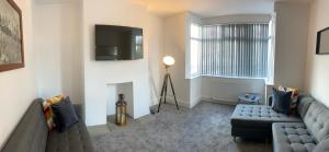 a living room with a couch and a tv on the wall at Bessie House Free Parking Doncaster Racecourse Wildlife Park Eco Power Stadium A1 M18 M1 M62 in Doncaster
