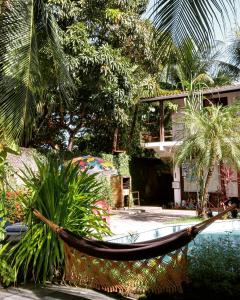 a hammock in front of a house with palm trees at Exclusive Guest House in Porto De Galinhas