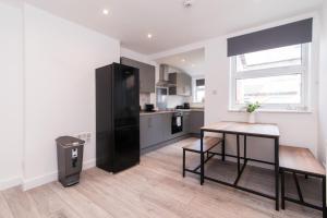 a kitchen with a table and a black refrigerator at Thurgarton House - Cosy and Calm 2bed in Nottingham