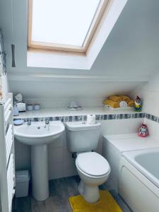bagno con servizi igienici, lavandino e finestra di Rosewood Guest House a Swindon