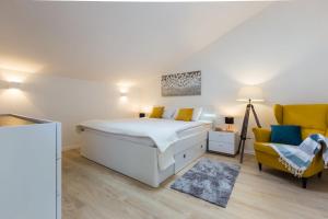 a bedroom with a bed and a yellow chair at Kuki apartment with balcony in Zadar