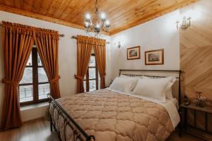 a bedroom with a large bed and two windows at Hotel SS KEKEZI in Gjirokastër