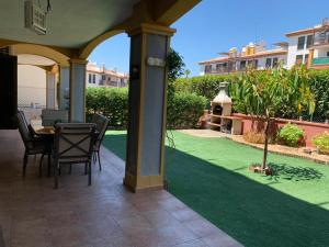 patio ze stołem i krzesłami oraz zielonym trawnikiem w obiekcie Apartamento con jardín privado y acceso a piscina w mieście Huelva
