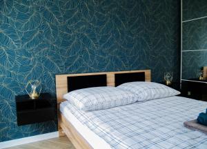 Schlafzimmer mit einem Bett mit blauer Wand in der Unterkunft Nowoczesny Apartament z widokiem na jezioro in Charzykowy