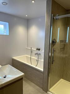 y baño con bañera, lavamanos y ducha. en Aurora - Self Catering, Kirkwall, Quiet Location with Luxury Hot Tub, en Islas Orcadas