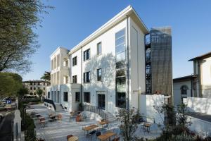 a white building with tables and chairs in front of it at YellowSquare Florence in Florence