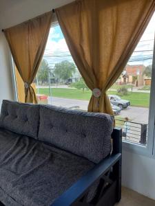 un sofá frente a una ventana con cortinas en Refugio del visitante en Chascomús