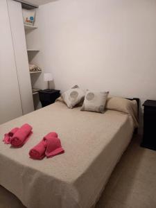 Una cama con dos toallas rosas encima. en Refugio del visitante en Chascomús