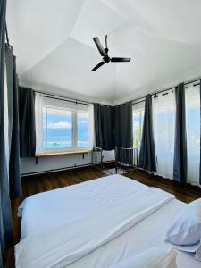 Schlafzimmer mit einem großen Bett und einem Deckenventilator in der Unterkunft Hiraeth island home in Guraidhoo