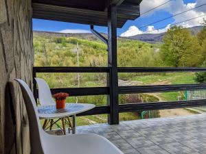 a table and chairs on a balcony with a view at Hill House Valiug Crivaia in Văliug