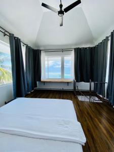 una camera con letto e ventilatore a soffitto di Hiraeth island home a Guraidhoo
