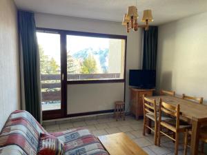 a living room with a couch and a table and a window at ORCIERES APPARTEMENT 6 PERSONNES AVEC PARKING in Orcières