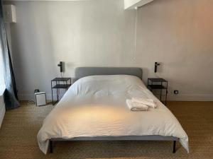 ein Schlafzimmer mit einem weißen Bett und zwei Tischen in der Unterkunft Laboutique2 in Lormes