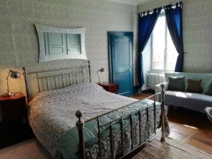 a bedroom with a bed and a window and a couch at 3 Place des Arbres, Chambres D'Hôtes, Felletin in Felletin