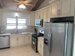 a kitchen with white cabinets and a stainless steel refrigerator at Oceanfront 3 bedrooms, 4beds, AC, WiFi, luxury villa in Woodlands