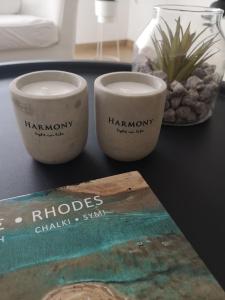 two cups sitting on a table next to a book at Harmony Elegant Central Apartment in Rhodes Town