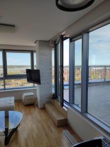 ein Wohnzimmer mit großen Fenstern und einem Flachbild-TV in der Unterkunft Sunset Terrace Apartment in Klaipėda