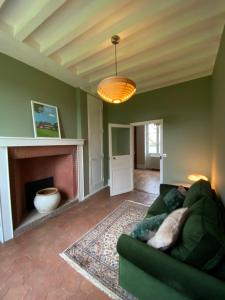 a living room with a green couch and a fireplace at Domaine de Chauvincourt in Chauvincourt