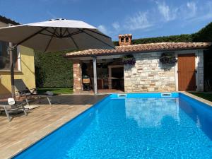 a swimming pool with an umbrella next to a house at Villa Eva Karigador in Novigrad Istria