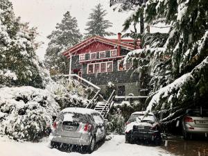 two cars parked in front of a house covered in snow at La Miralejos in San Carlos de Bariloche