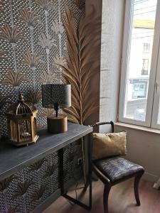 a desk with a lamp and a chair next to a wall at La Canopée in Cholet