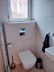 La salle de bains est pourvue de toilettes, d'un lavabo et d'une fenêtre. dans l'établissement Apartament Zacisze OLO, à Niechorze