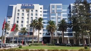 a hotel with palm trees in front of a building at Du Haut Standing au coeur du Parc et Plage à 180 m in Mohammedia