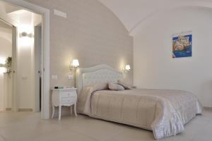 a white bedroom with a large bed and a table at Sirena Apartment in Minori