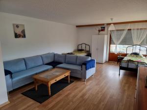 uma sala de estar com um sofá azul e uma mesa em Appartment Gude, Ulm- Stuttgart em Heroldstatt