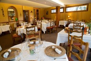 een eetkamer met witte tafels en stoelen met glazen bij Auberge Saint Fleuret in Estaing