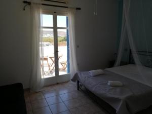 a bedroom with a bed and a door to a balcony at Papikinou Studios in Adamantas