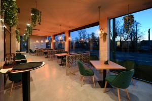 ein Restaurant mit Tischen, grünen Stühlen und Fenstern in der Unterkunft Hotel Xemar in Arad
