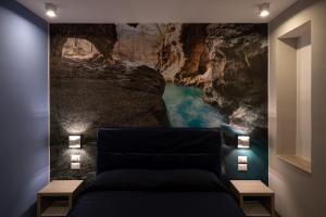 Habitación con cama y mural en la pared de una cueva. en Hotel La Sorgente HS, en Paestum