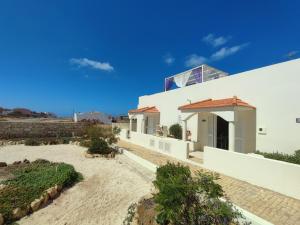una casa bianca sulla spiaggia con un cielo azzurro di Casa Djarmai Apartments a Vila do Maio