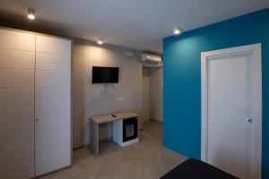 Cette chambre est dotée d'un mur bleu, d'une table et d'une télévision. dans l'établissement Hotel La Sorgente HS, à Paestum
