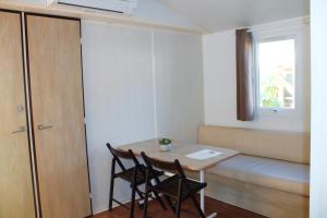 une petite chambre avec une table, des chaises et une fenêtre dans l'établissement Camping Lou Cabasson, à Bormes-les-Mimosas