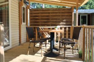 une terrasse en bois avec une table et des chaises. dans l'établissement Camping Lou Cabasson, à Bormes-les-Mimosas