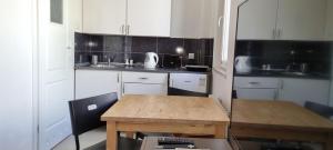 eine kleine Küche mit weißen Schränken und einem Holztisch in der Unterkunft Pokoje Gościnne Apartamenty in Misdroy